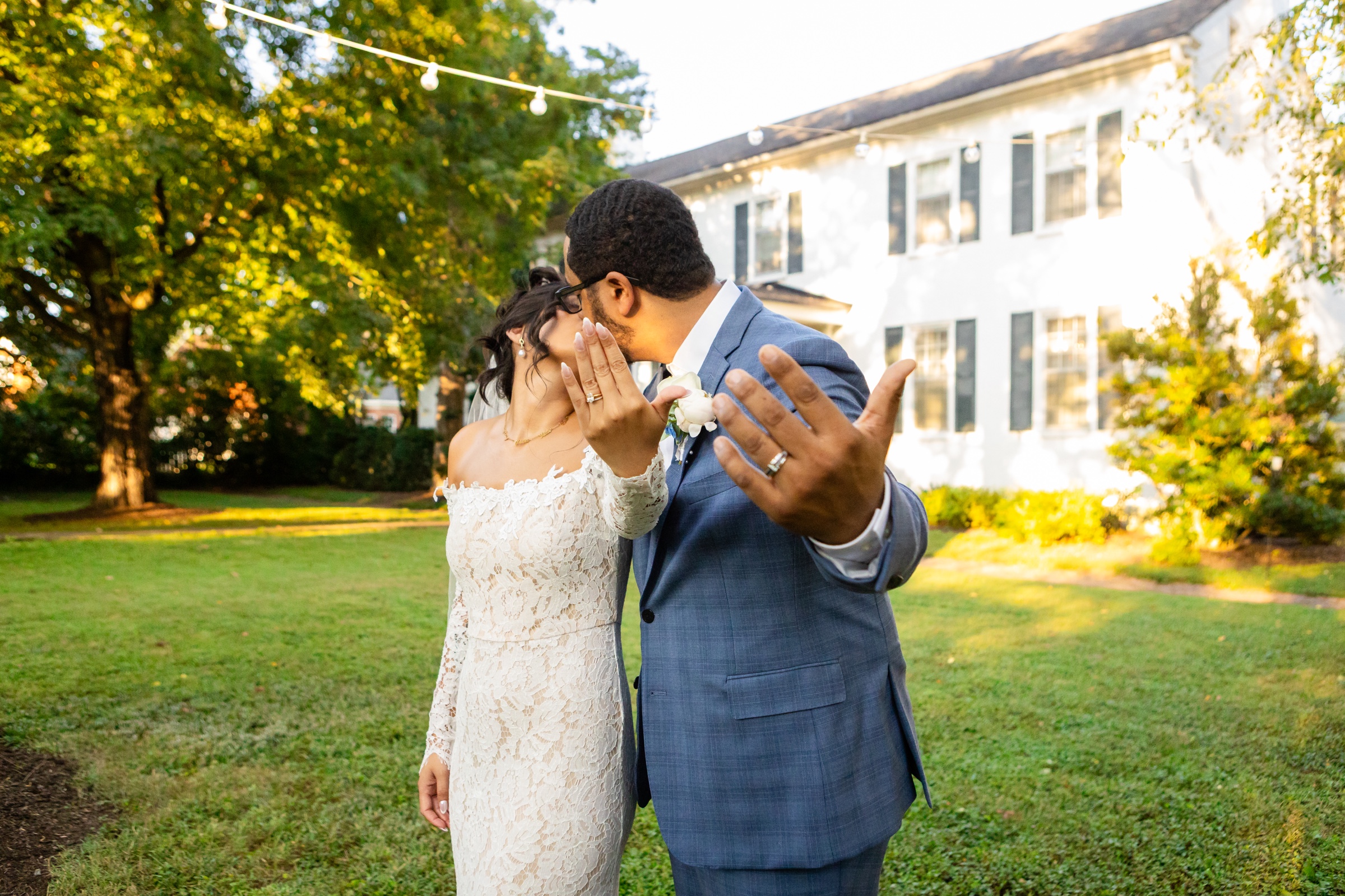 Couple showing wedding rings with mansion in background